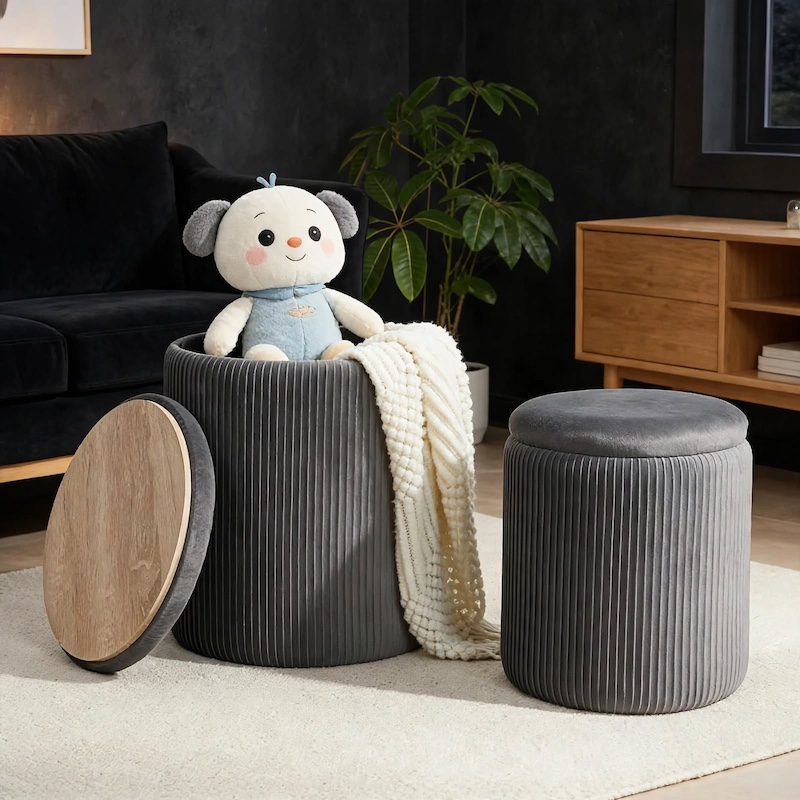 A grey ribbed velvet Set Of 2 Round Storage Ottomans with Lids styled in a living room with a plush white throw blanket and a cute toy.
