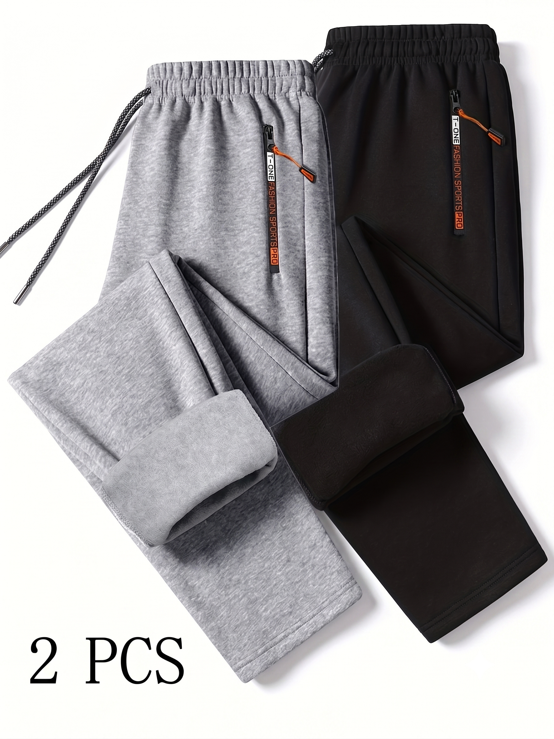 comfortable 2pcs Men's Winter Warm Fleece Sweatpants with Zipper Pockets Casual Trousers Track Pants Drawstring Waist for Running Workout Gym Outdoors for Fall Winter 11 A professional flat lay studio image on a white background showing a two-piece collection of comfortable Men's Winter Warm Fleece Track Pants in light grey and solid black. The joggers are arranged overlapping one another, with the lower leg segment of the light grey pair folded up to showcase the thick, color-matched inner fleece insulation lining. The elastic waistbands feature long speckled drawstrings and high-contrast vertical zippered side pockets with branded pulls and orange cord tabs. Large serif text reading 2 PCS is printed in the bottom left corner.