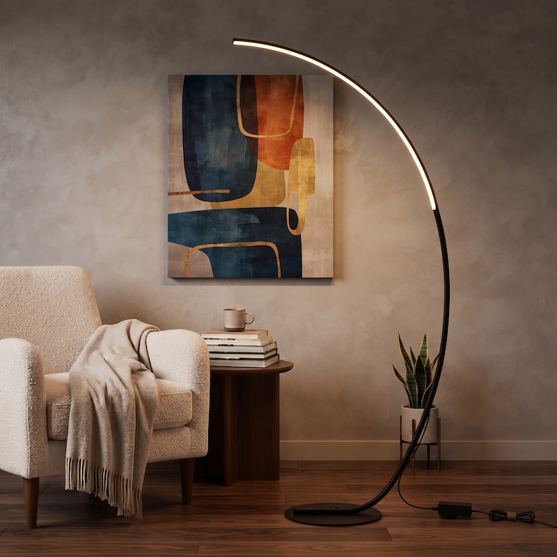 Wide-angle shot of a sophisticated living room at night, featuring a beige armchair, a wood side table with decor, a large abstract art piece, and the Arched Standing Reading Floor Lamp casting a warm arch of light.