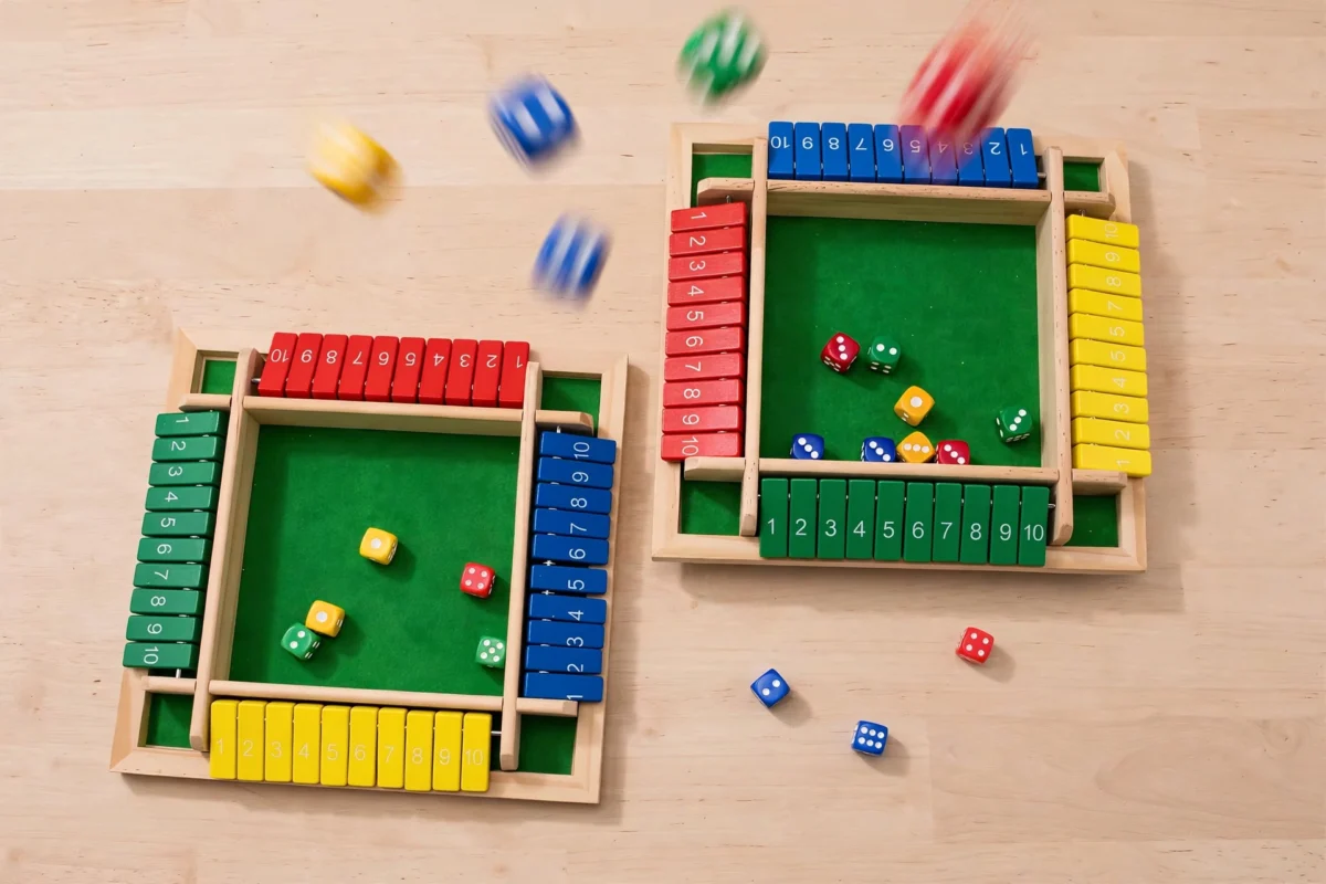 Wooden Shut the Box Dice Game, Classic Family Board Game for Math & Decision-Making Skills, for 2-6 Players, Perfect for Parties Birthdays Halloween and Christmas Gifts, Ideal for Family Game Nights and Stocking Stuffers 4 Motion blur action shot of dice flying over two Wooden Shut the Box Dice Game boards on a clean wooden tabletop surface.