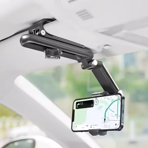 A professional product visualization of the Car Phone Holder with a 1080° Rotating Sun. The matte black hardware is securely clamped to a vehicle's sun visor, holding a smartphone in landscape orientation for GPS navigation. The system features a sophisticated folding telescopic arm with silver-accented pivot points and an adjustable slide rail with a primary tension knob. Additional graphics demonstrate the unit's "Folding Storage" state, showing it collapsed against the visor to occupy "No Space." The background shows a soft-focus road view, emphasizing driver-centric ergonomic placement and stability.