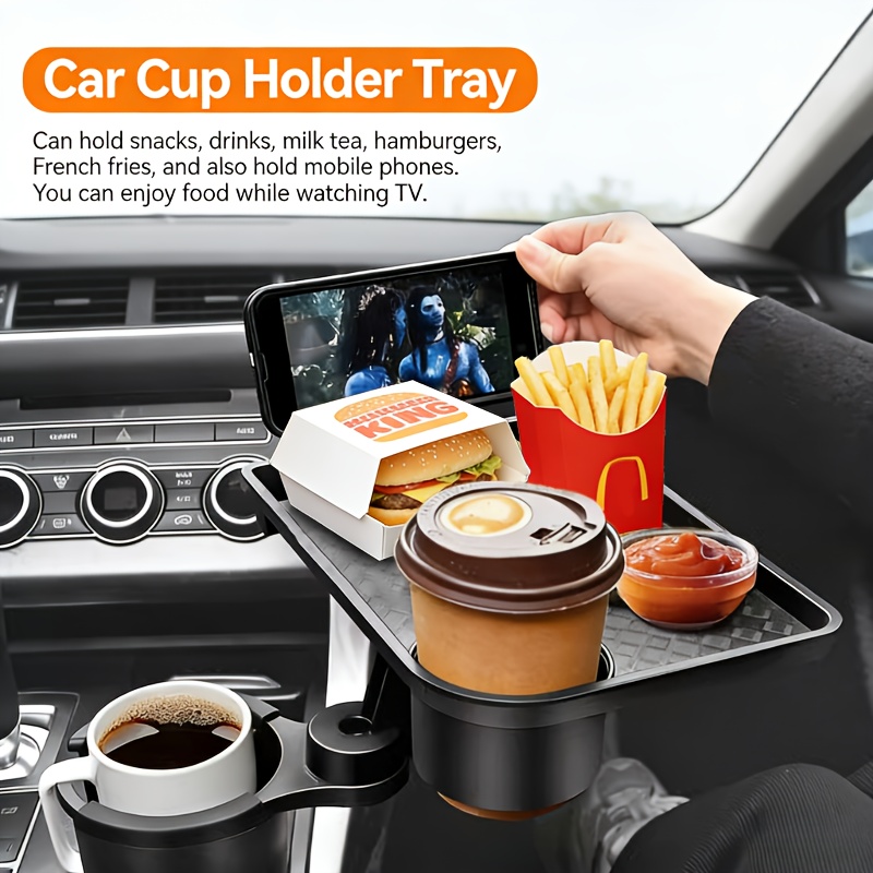 Operational Infrastructure Node: Car Cup Holder Expansion Tray with 40lb Load Capacity and 360° Rotating Mechanical Base for Superior Cabin Utility 7 A professional high-definition lifestyle photograph of the Car Cup Holder Expansion Tray in a vehicle interior. The matte black unit is anchored in the center console, featuring a lower cup holder supporting a white mug and an upper swivel tray. The tray holds a smartphone in landscape mode (displaying a movie), a hamburger in a box, a container of French fries, a dipping sauce bowl, and a disposable coffee cup in the integrated secondary well. A hand is shown adjusting the smartphone. The background features the vehicle's dashboard and steering wheel in soft focus. The focus is sharp on the tray's textured surface and its diverse cargo.