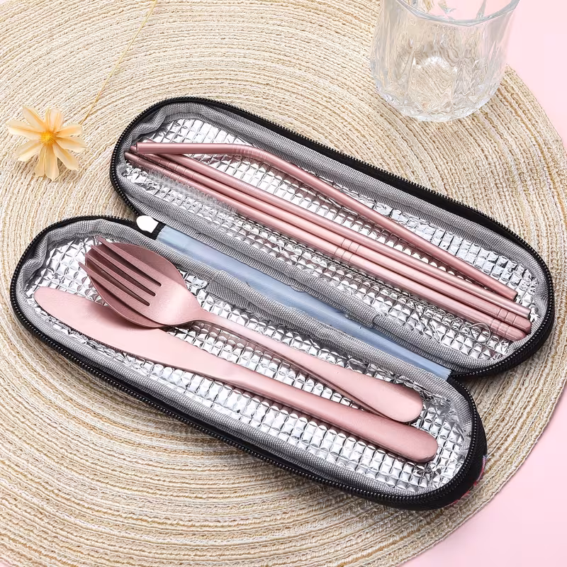 reliable Unyielding Travel Utensils Reusable Silverware Set: Professional-Grade Stainless Steel Cutlery in a Weatherproof Armor Case 4 An organized travel utensils reusable silverware set is displayed alongside its matching tactical-green carrying pouch on a blurred outdoor surface. The six silver-colored stainless steel utensils are fanned out, including a serrated knife, a dinner fork, a large spoon, a metal straw, a pair of anti-slip chopsticks, and a thin cleaning brush. All items feature a sleek, durable