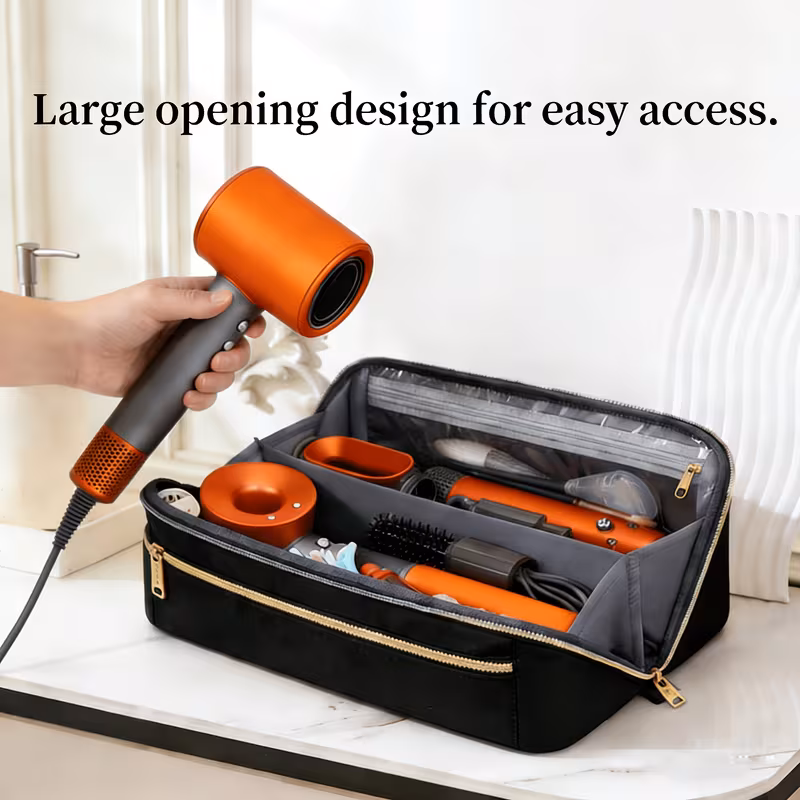 3-in-1 Clutch Bag Hot Hair Tools Travel Bag – Large Capacity Wide-Open Hair Accessory Case & Professional Heat-Safe Styling Mat 11 A hand holds an orange and grey hair dryer over an open black Clutch Bag Hot Hair Tools Travel Bag, which reveals neatly organized matching copper-toned styling tools, combs, and clips in its compartments and clear pockets.