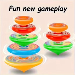 A high-definition professional product photograph. A naturally manicured hand with glossy peach-nude nails holds a Colorful Spinning Multi-layer Spinning Toy on a gray linen surface. Next to the hand sits a matte black bottle of 'Jelly Ice Nude' AL14 nail polish and a matching color swatch card. The hardware is a spherical, multi-layer kinetic device consisting of concentric polymer rings in a vibrant spectral array (yellow, blue, green, red, purple). The background is a softly blurred interior with large windows and potted greenery under diffused natural light. Every detail, from the smooth matte finish of the rings to the sharp branding on the polish bottle, is rendered in immaculate focus.