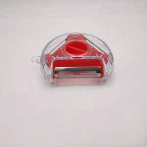 A close-up, top-down photograph against a clean white background, featuring a straight red color fruit and vegetable peeler. The tool has a vibrant red ergonomic handle made of durable, non-slip material and a polished stainless steel blade assembly at the top. The straight blade is flanked by protective guide bars, and an integrated eye remover tool is visible on the plastic head adjacent to the blade. The handle is ribbed for grip near the blade and includes a hanging loop at the base.