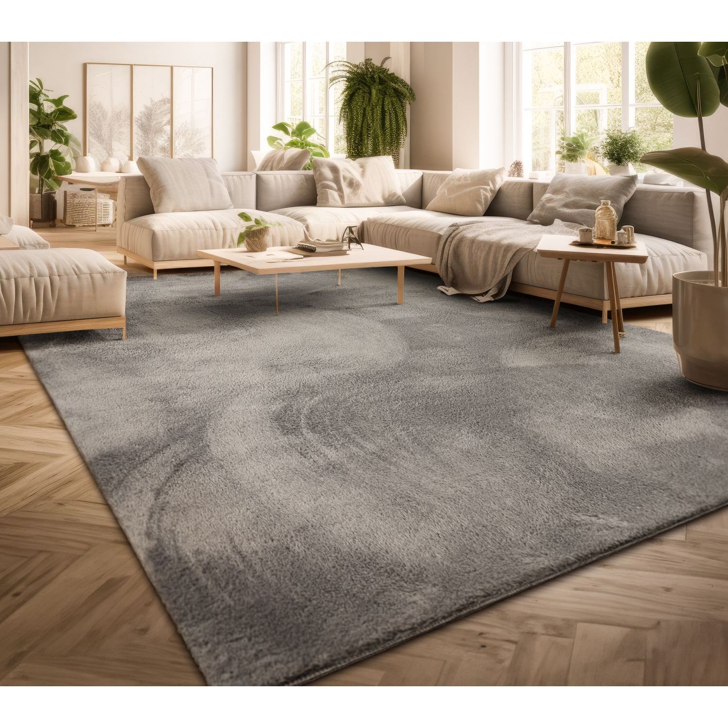 exclusive Modern Living Room Rug – Washable Short Pile Area Rug | Stain-Resistant & Non-Slip Premium Polyester 5 A large dark gray modern living room rug laid across a light herringbone hardwood floor beneath a contemporary cream colored sectional sofa and minimalist wooden coffee tables in a bright sunlit room filled with houseplants